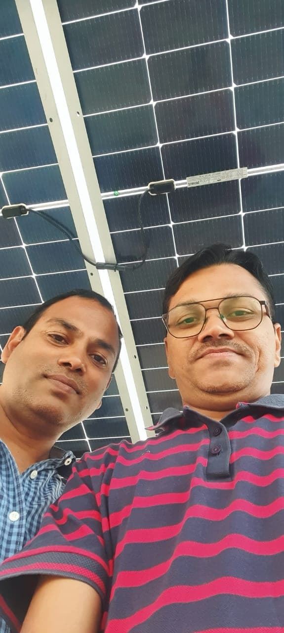Customer with Genius Solar engineer beneath the mono solar modules of his new rooftop system, Indore