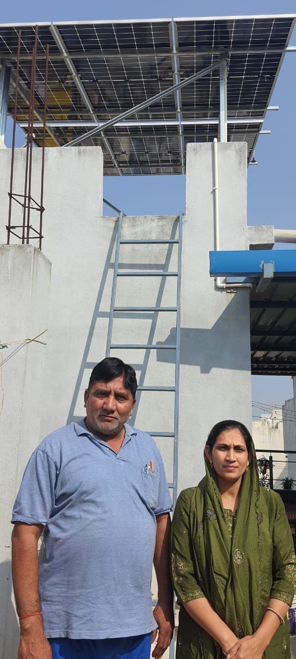 Indore couple standing on their terrace below a newly installed raised solar panel system
