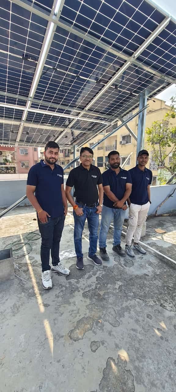 Genius Solar installation team standing under a newly completed rooftop solar array in Indore