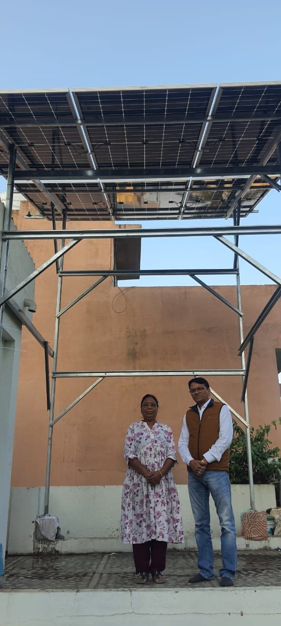 Husband and wife homeowners under their new elevated rooftop solar array in Indore