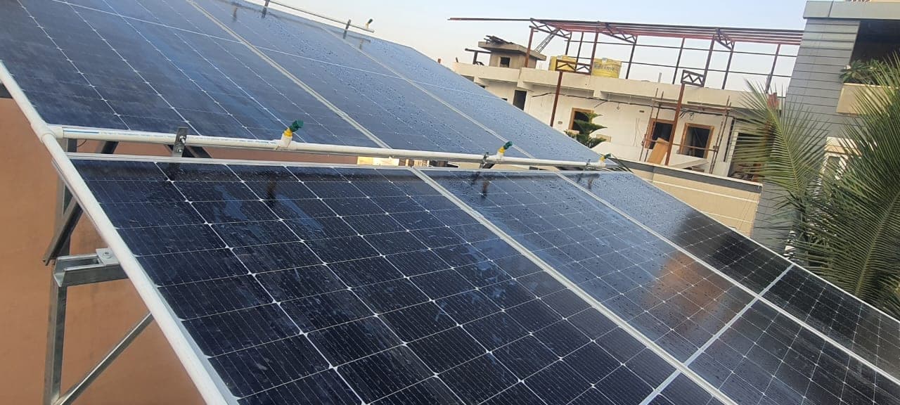 South-facing tilted solar panels on a rooftop in Indore with trees in the background